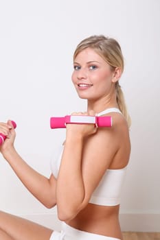 Beautiful blond woman lifting dumbbells in fitness gym