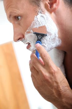 Handsome man shaving in bathroom