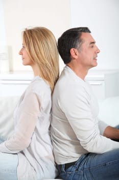 Couple sitting back to back on sofa