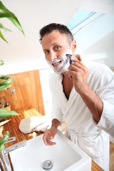 Handsome man shaving in bathroom