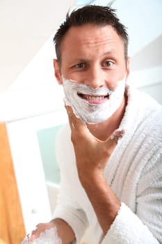 Handsome man shaving in bathroom