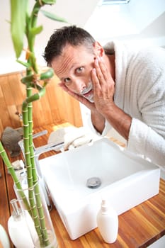 Handsome man shaving in bathroom