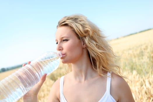 beautiful blond woman drinking water fom bottle