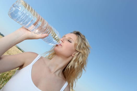 beautiful blond woman drinking water fom bottle