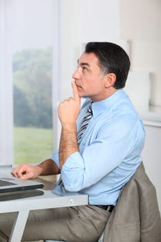 Businessman sitting at his desk with hand on chin