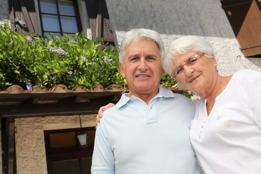Senior couple standing in front of a house