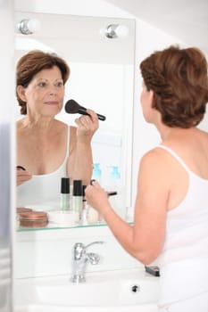 Closeup of senior woman putting makeup on