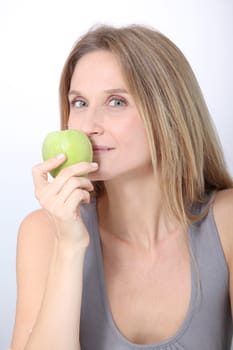 Beautiful blond woman eating green apple