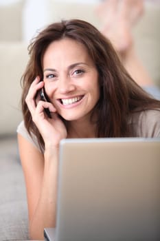 Woman on couch with laptop computer and telephone