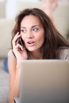 Woman on couch with laptop computer and telephone