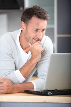 Man with laptop computer in kitchen