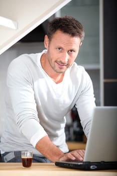 Man with laptop computer in kitchen