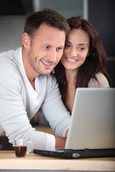 Couple at home connected on internet with laptop computer
