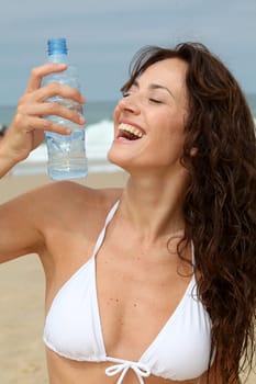 Beautiful woman drinking water at the beach