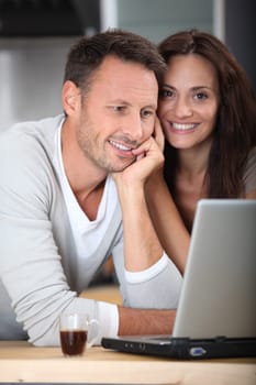 Couple at home connected on internet with laptop computer
