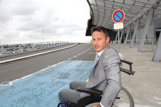Businessman in wheelchair waiting for a taxi