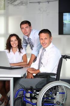 Businessman in wheelchair working in the office with colleagues