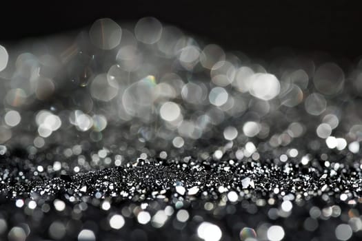Sparkling silver and black bokeh abstract background with blurred lights.