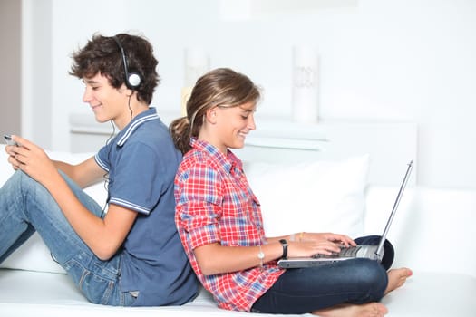 Teenagers with music player and computer at home