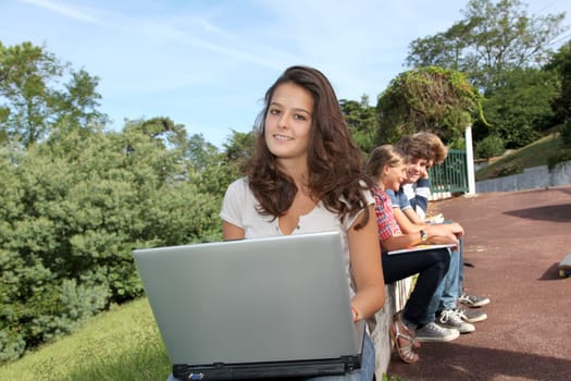 Teenagers sitting outside with laptop computer
