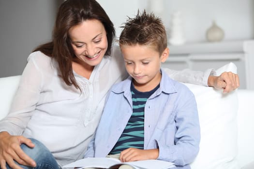 mother and son reading book on a sofa