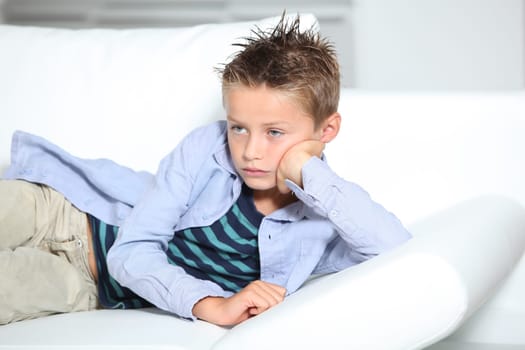 Young boy laying on a sofa at home
