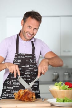 Man in kitchen with apron cooking chicken