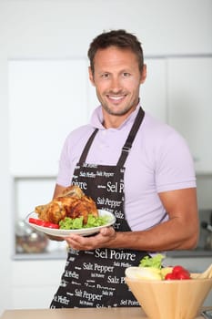 Man in kitchen with apron cooking chicken