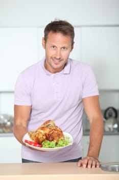 Man in kitchen with apron cooking chicken