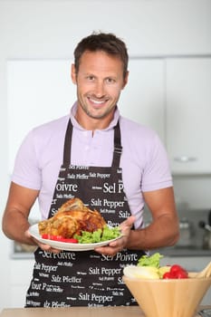 Man in kitchen with apron cooking chicken