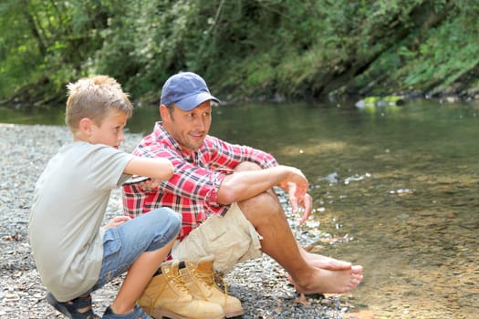 Father and son throwing pebble in river