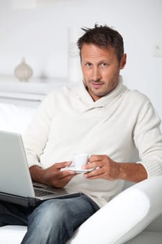 Man with laptop computer sitting in sofa
