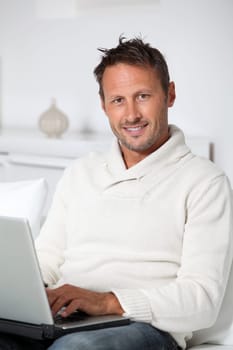Man with laptop computer sitting in sofa
