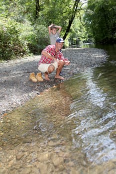 Father and son throwing pebble in river
