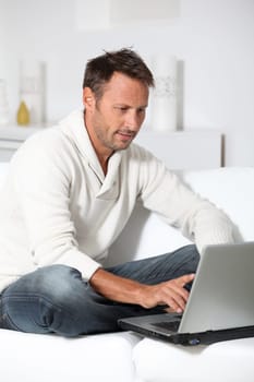 Man with laptop computer sitting in sofa