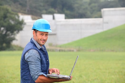Engineer standing in front of dam under construction