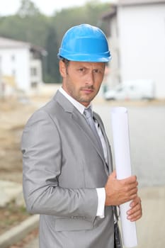 Businessman with helmet checking site under construction