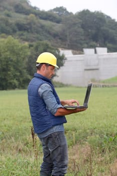 Engineer standing in front of dam under construction