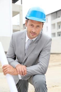 Businessman with helmet checking site under construction