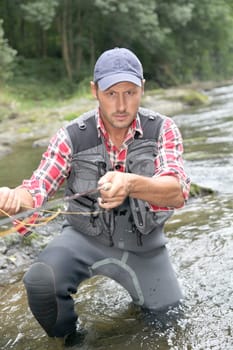 Fisherman in river with fly fishing rod