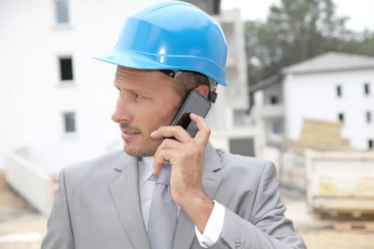 Businessman with helmet checking site under construction