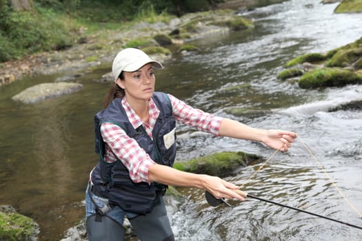 woman with fly fishing rod in river