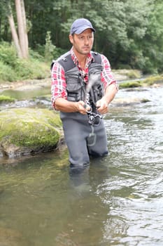 Fisherman in river with fishing rod