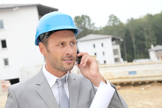 Businessman with helmet checking site under construction