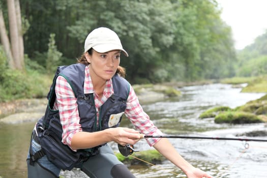 woman with fly fishing rod in river