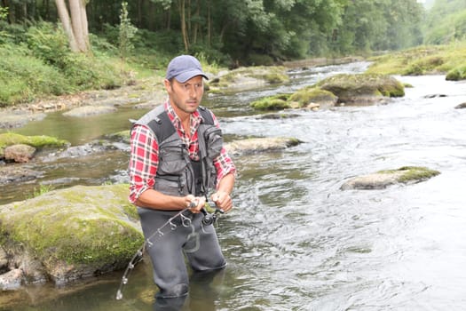 Fisherman in river with fishing rod