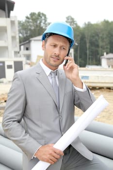 Businessman with helmet checking site under construction