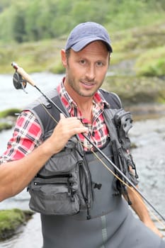 Closeup of fly-fisherman holding fishing rod in river