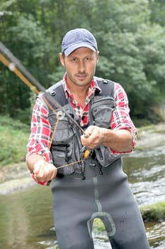 Fisherman in river with fly fishing rod