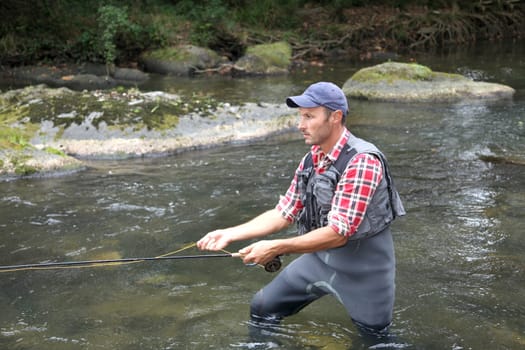 Fisherman in river with fly fishing line